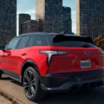The 2025 Chevrolet Blazer EV SS exhibits its sculpted rear styling with distinctive LED taillights, floating roof design with black contrasting elements, and aerodynamic profile against a modern cityscape.