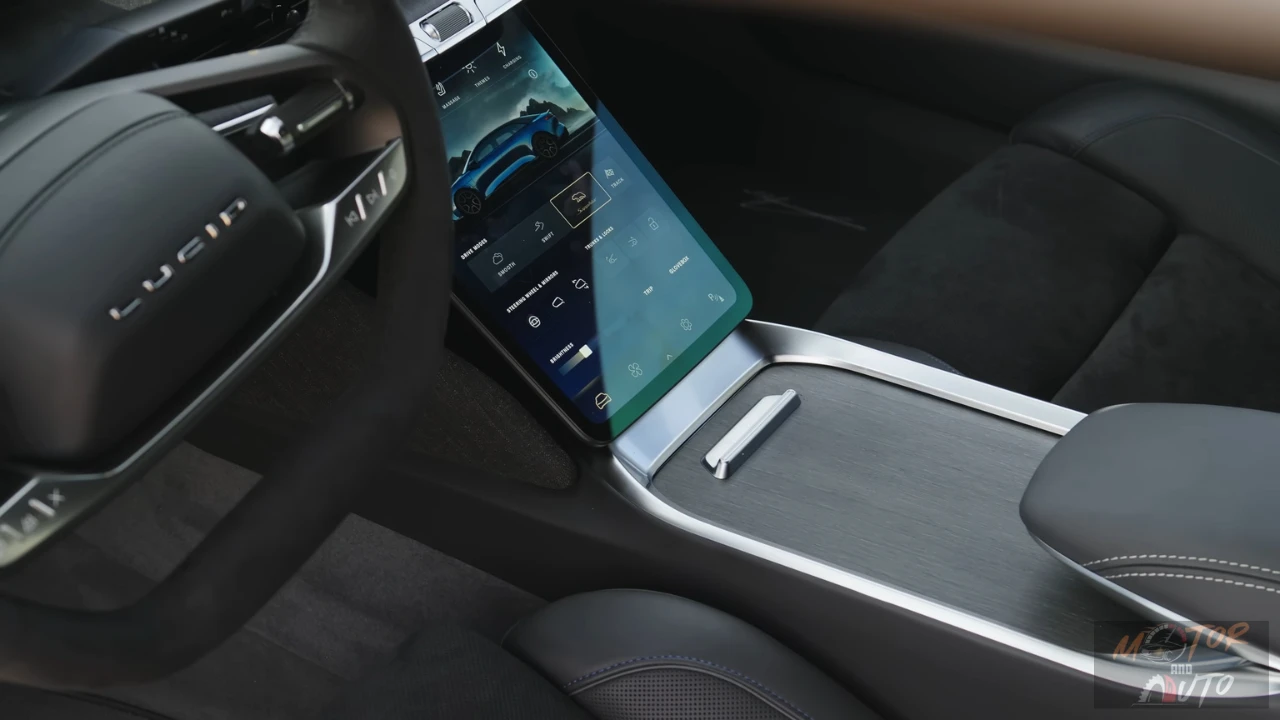 Angled view of the 2025 Lucid Air's center console touchscreen showing the vehicle settings menu with drive mode controls and a blue car graphic against a dark background.