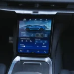Close-up of the 2025 Lucid Air's touchscreen showing the drive mode selection interface with mode options displayed against a blue background featuring a side profile image of the car.