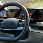 Close-up view of the 2025 Lucid Air's digital instrument cluster showing speedometer, drive mode indicator, and navigation information on the curved display with the steering wheel visible in the foreground.