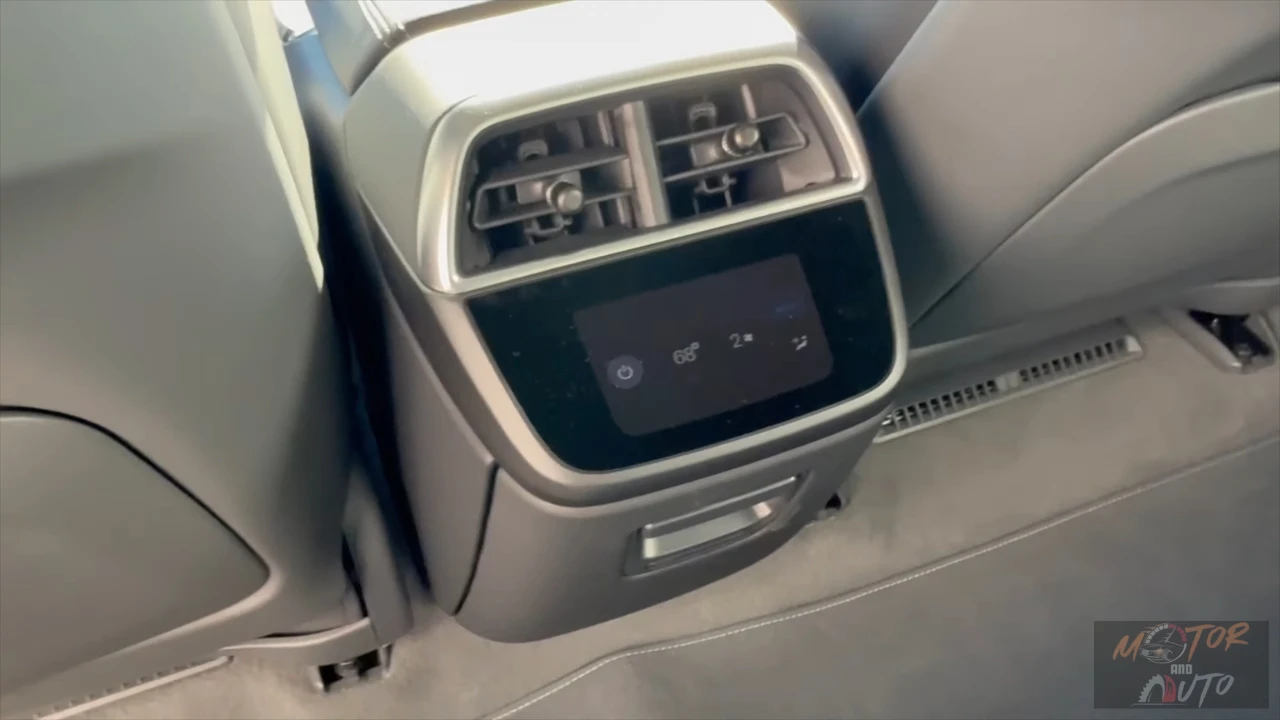 Close-up of the 2025 Lucid Air's rear center console showing climate control vents, a small touchscreen display for temperature adjustment, and silver-trimmed housing integrated into the light gray interior with premium upholstery visible.