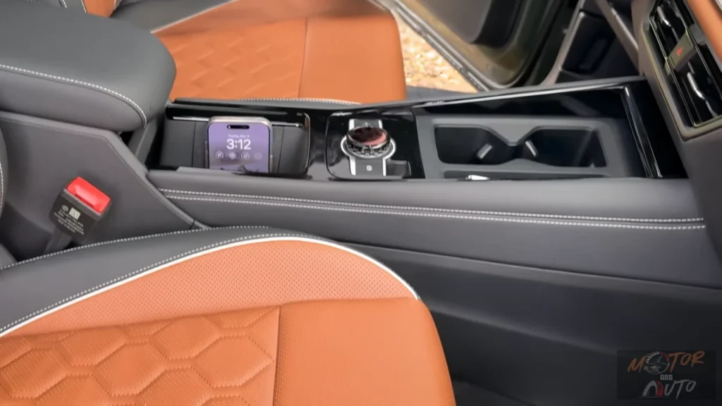 Close-up of 2025 Volkswagen Tiguan center console showing storage compartment, wireless charging pad with phone, and premium leather materials