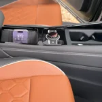 Close-up of 2025 Volkswagen Tiguan center console showing storage compartment, wireless charging pad with phone, and premium leather materials