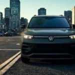 Front view of 2025 Volkswagen Tiguan at dusk with LED headlights illuminated in urban setting showing lighting technology