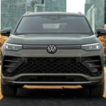 Front view of 2025 Volkswagen Tiguan in gray showing LED headlights, large black grille, and modern SUV design in urban setting