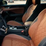 Front seats of 2025 Volkswagen Tiguan showing quilted brown leather upholstery with contrast stitching and premium seat design