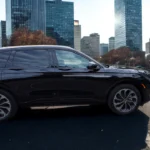 Full side profile view of 2025 Lincoln Nautilus showing complete vehicle proportions, wheel design, window configuration, and flowing body lines against downtown city backdrop