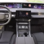 Driver's perspective of 2025 Lincoln Nautilus interior showing the full 48-inch curved display with navigation map, music controls, weather information, and squared steering wheel
