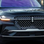 Close-up front view of 2025 Lincoln Nautilus showing diamond mesh grille pattern, LED headlights with amber turn signals, illuminated Lincoln star logo, and premium chrome detailing