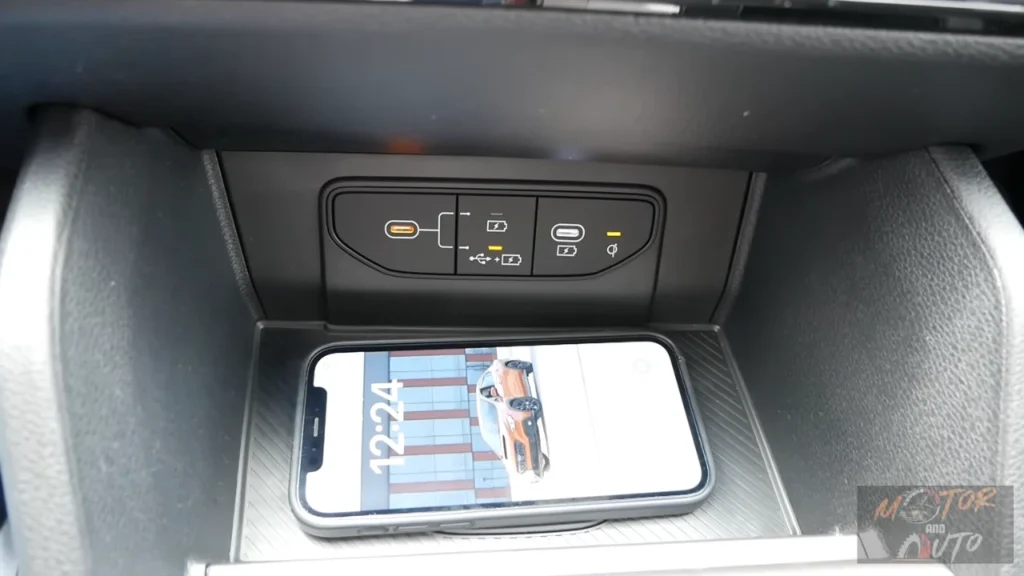 Center console of 2026 Kia Sportage showing wireless phone charging pad with smartphone and dual USB-C ports for device connectivity and charging