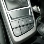 Close-up of 2026 Kia Sportage center console showing control buttons for hill descent, auto start-stop, parking assist, auto hold, and camera system activation