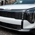 Close-up of 2026 Kia Sportage lower front bumper showing parking sensors, fog light area, black protective cladding, and modern bumper design