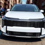 Close-up of 2026 Kia Sportage lower front bumper showing parking sensors, fog light area, black protective cladding, and modern bumper design
