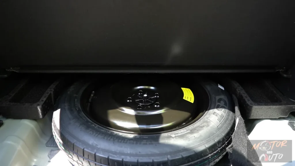 Under-floor view of 2026 Kia Sportage cargo area showing spare tire compartment with full-size spare wheel and tire changing tools