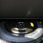 Under-floor view of 2026 Kia Sportage cargo area showing spare tire compartment with full-size spare wheel and tire changing tools