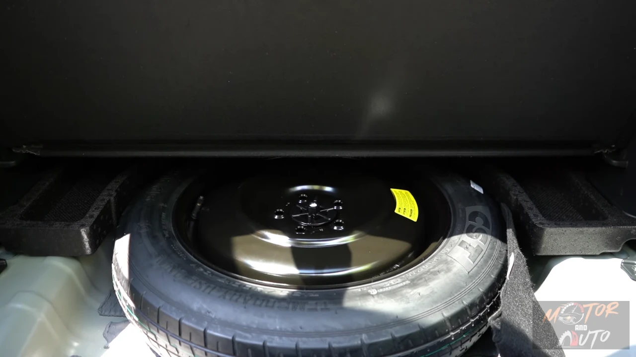 Under-floor view of 2026 Kia Sportage cargo area showing spare tire compartment with full-size spare wheel and tire changing tools