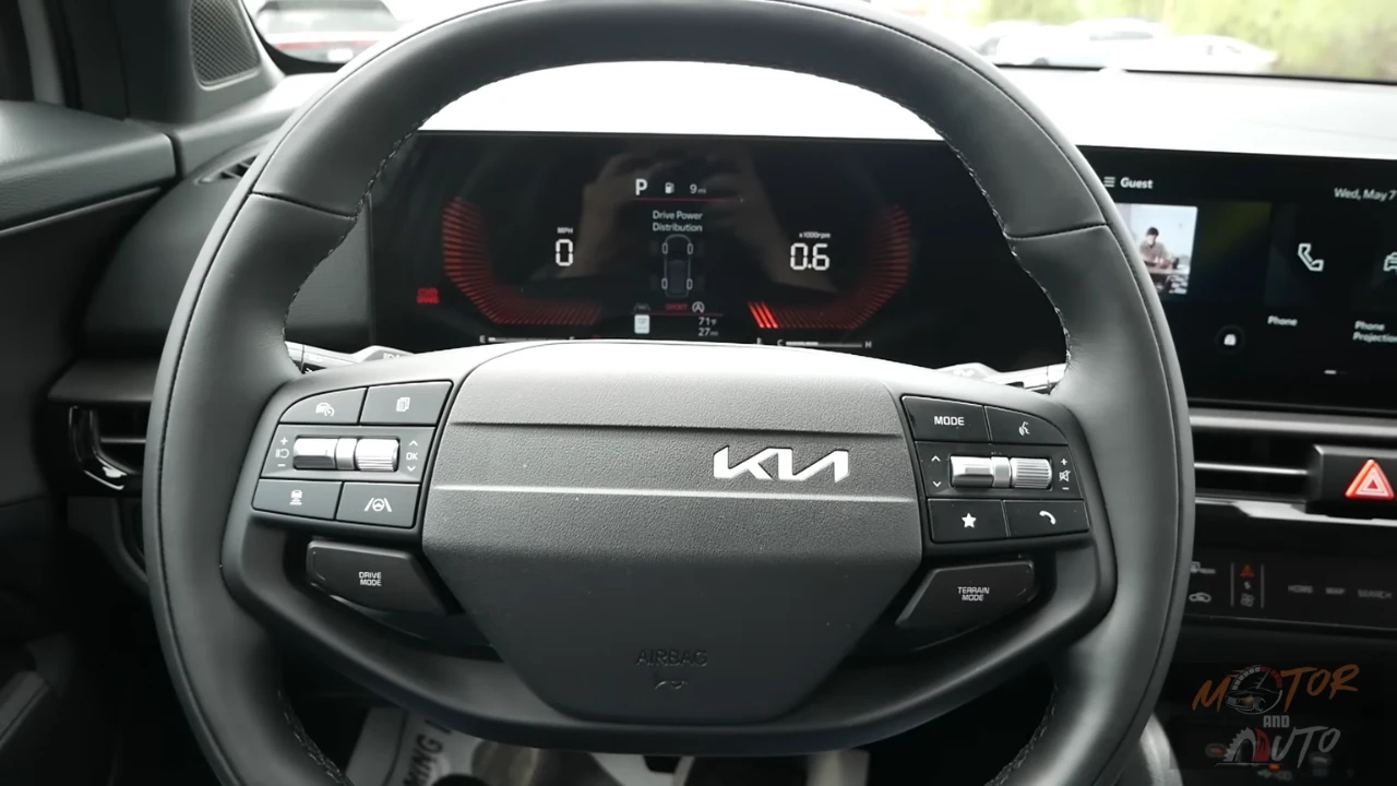 Close-up view of 2026 Kia Sportage new yoke-shaped steering wheel with physical control buttons and digital gauge cluster showing drive modes and vehicle information